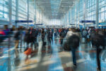 Crowded airport terminal with numerous travelers walking quickly towards their destinations, A bustling airport terminal with travelers rushing to their gates